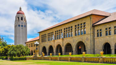 El césped delantero y el edificio principal de la Universidad de Stanford en un día soleado, con el campanario al fondo